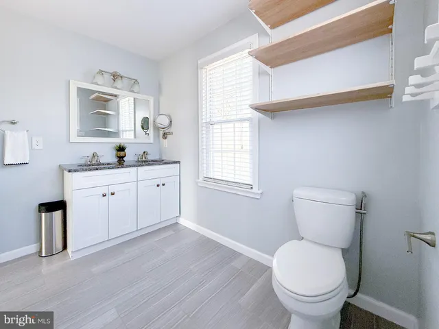 a spacious bathroom with a granite countertop toilet a sink and a window