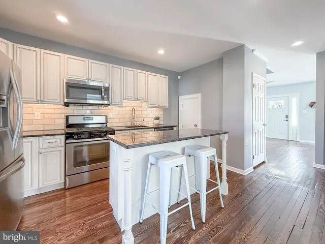 a kitchen with granite countertop a refrigerator stove top oven and sink