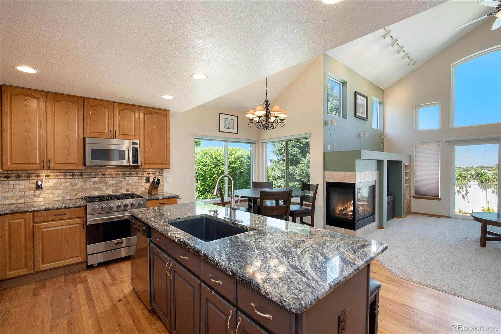 a kitchen with granite countertop a sink dishwasher stove and oven with wooden floor