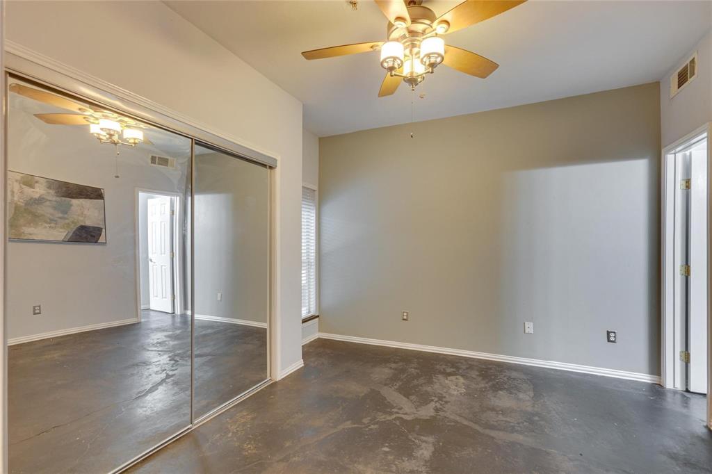 4104 North Hall Street, Unit 102 Dallas, TX 75219 - Photo 14 of 18 Spacious room featuring concrete flooring, a ceiling fan with integrated lighting, and a mirrored sliding closet door