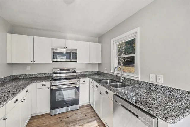 a kitchen with granite countertop white cabinets and white appliances