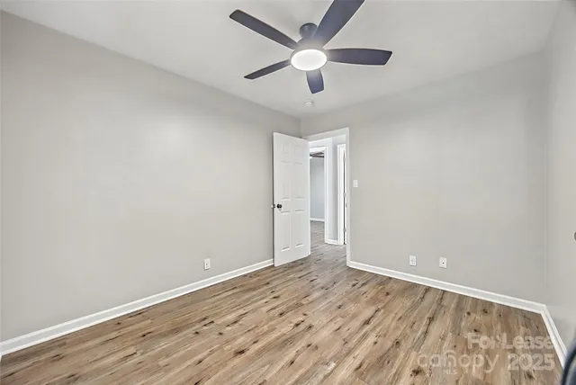 an empty room with wooden floor and ceiling fan