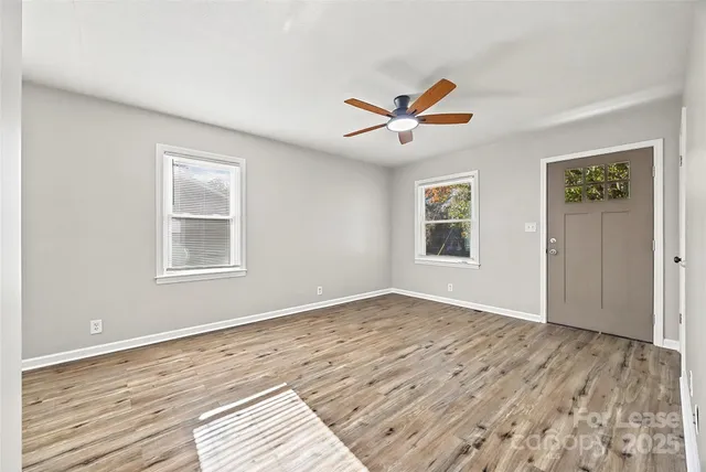 a view of an empty room with window and wooden floor