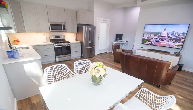 a kitchen with stainless steel appliances a refrigerator a sink a stove a dining table and chairs