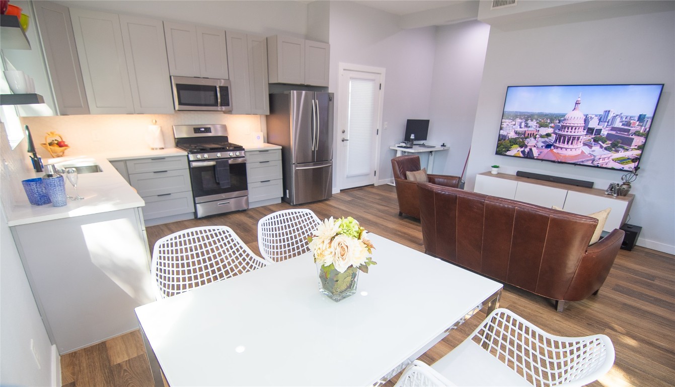 3508 Robinson Avenue, Unit B Austin, TX 78722 - Photo 4 of 17 a kitchen with stainless steel appliances a refrigerator a sink a stove a dining table and chairs