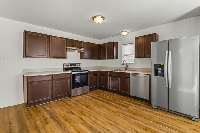 a kitchen with granite countertop a refrigerator stove top oven and sink