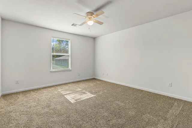 an empty room with windows and fan
