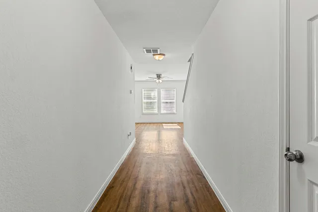 a view of a hallway with wooden floor and a window