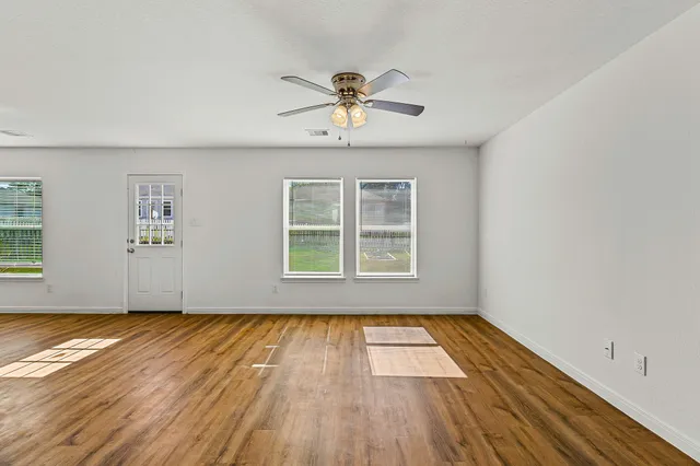 a view of empty room with wooden floor and fan