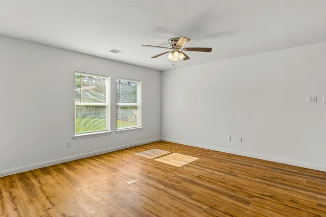 a view of empty room with wooden floor and fan