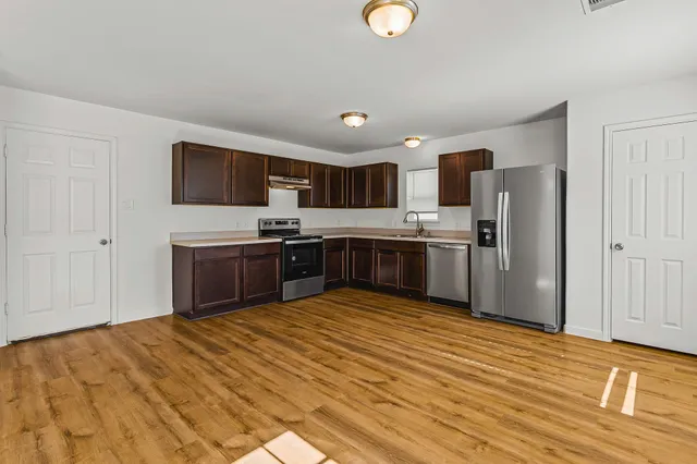 a large kitchen with stainless steel appliances granite countertop a stove refrigerator and a microwave