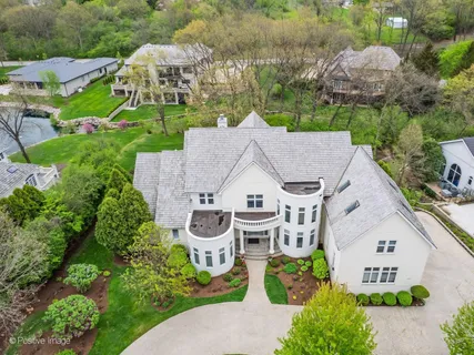 an aerial view of a house with yard and trees in the background
