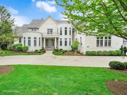 a front view of a house with garden and trees