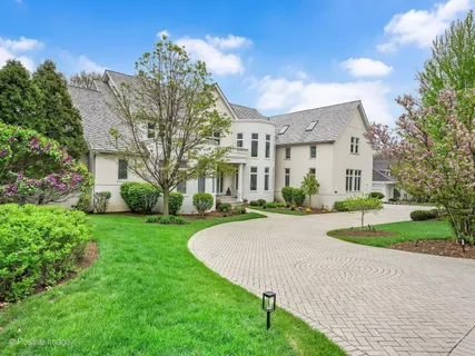 a view of a white house next to a yard with big trees