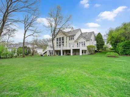 a view of a white house with a big yard and large trees