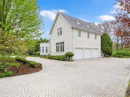 a view of a white house with a small yard plants and large tree
