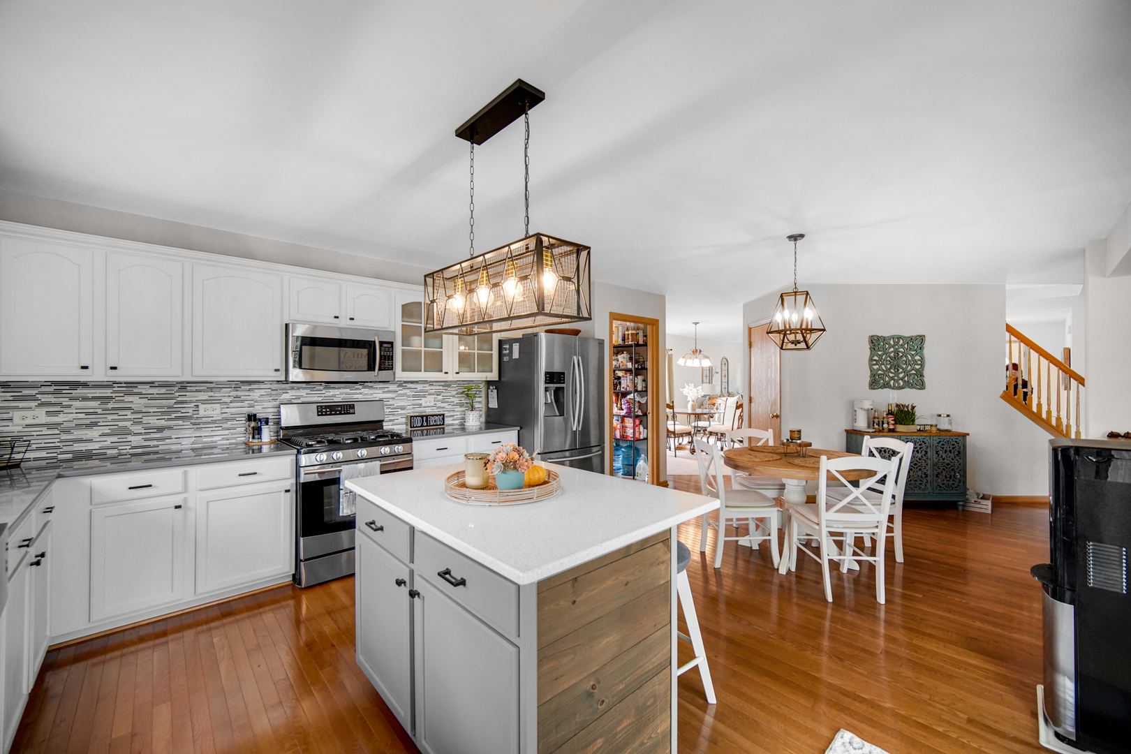 25421 Faraday Road Manhattan, IL 60442 - Photo 9 of 36 a open kitchen with stainless steel appliances granite countertop a stove refrigerator a dining table and chairs with wooden floor