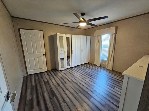 an empty room with wooden floor cabinet and windows
