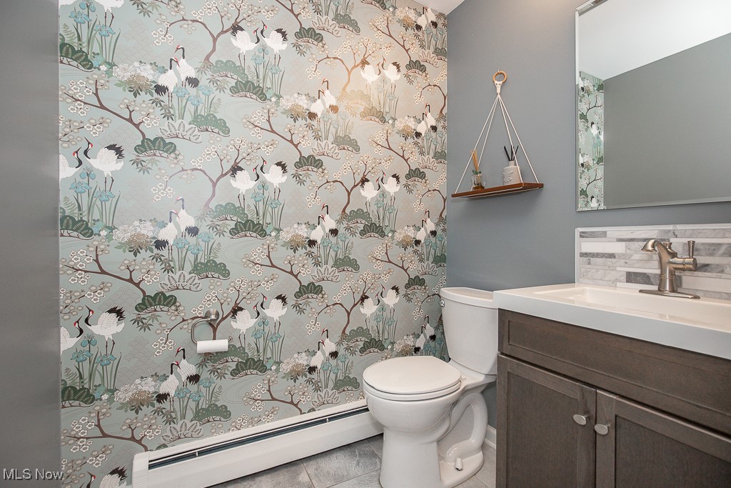 2969 Center Road Avon, OH 44011 - Photo 4 of 33 Bathroom with vanity, backsplash, tile patterned flooring, toilet, and a baseboard radiator