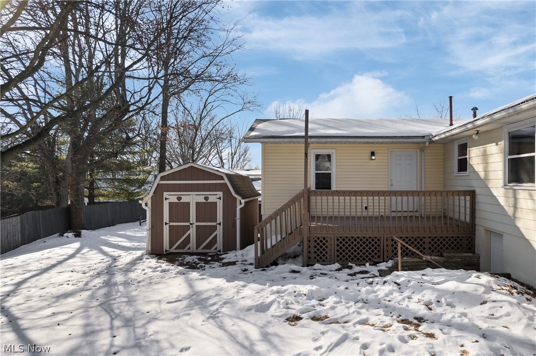 136 South Metzger Avenue Rittman, OH 44270 - Photo 19 of 33 Snow covered house with a storage shed, a fenced backyard, and a wooden deck