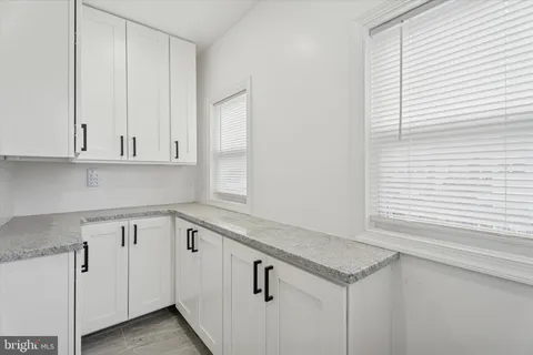 a kitchen with white cabinets and a window