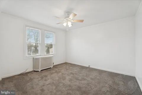 an empty room with chandelier fan and windows