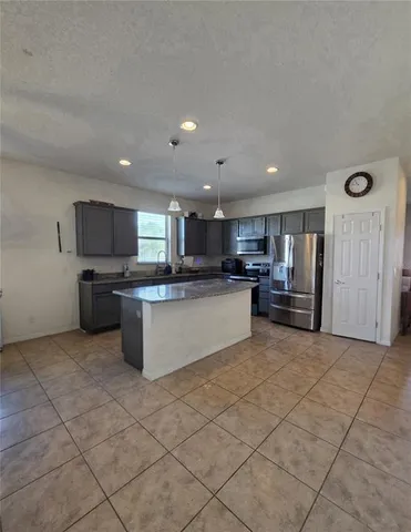 a large hall with stainless steel appliances granite countertop a sink and cabinets