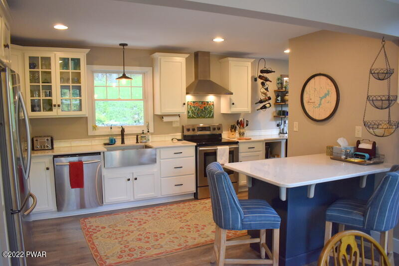 549 Finn Swamp Road Lakeville, PA 18438 - Photo 5 of 35 a kitchen with stainless steel appliances kitchen island granite countertop a stove a sink dishwasher and white cabinets with wooden floor