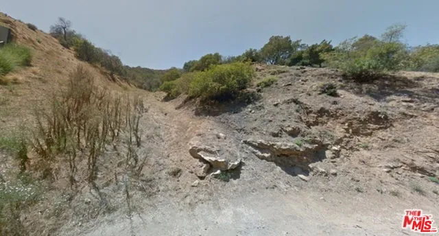 a view of a dry yard with wooden fence