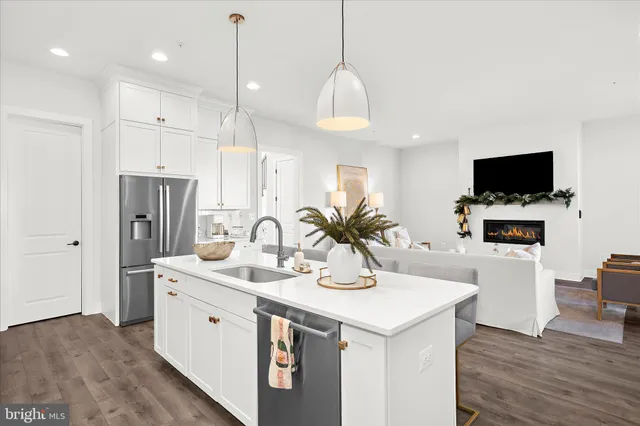 a kitchen with stainless steel appliances kitchen island granite countertop a table chairs and a view of living room