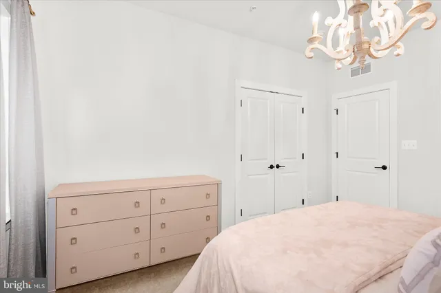 a spacious bedroom with a bed chandelier and a window