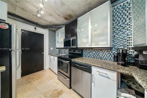 a kitchen with granite countertop a sink cabinets and stainless steel appliances
