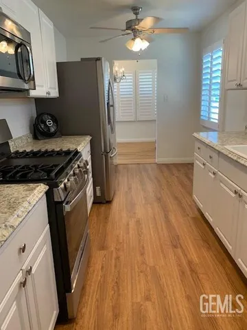 a kitchen with granite countertop a refrigerator a stove and wooden floor