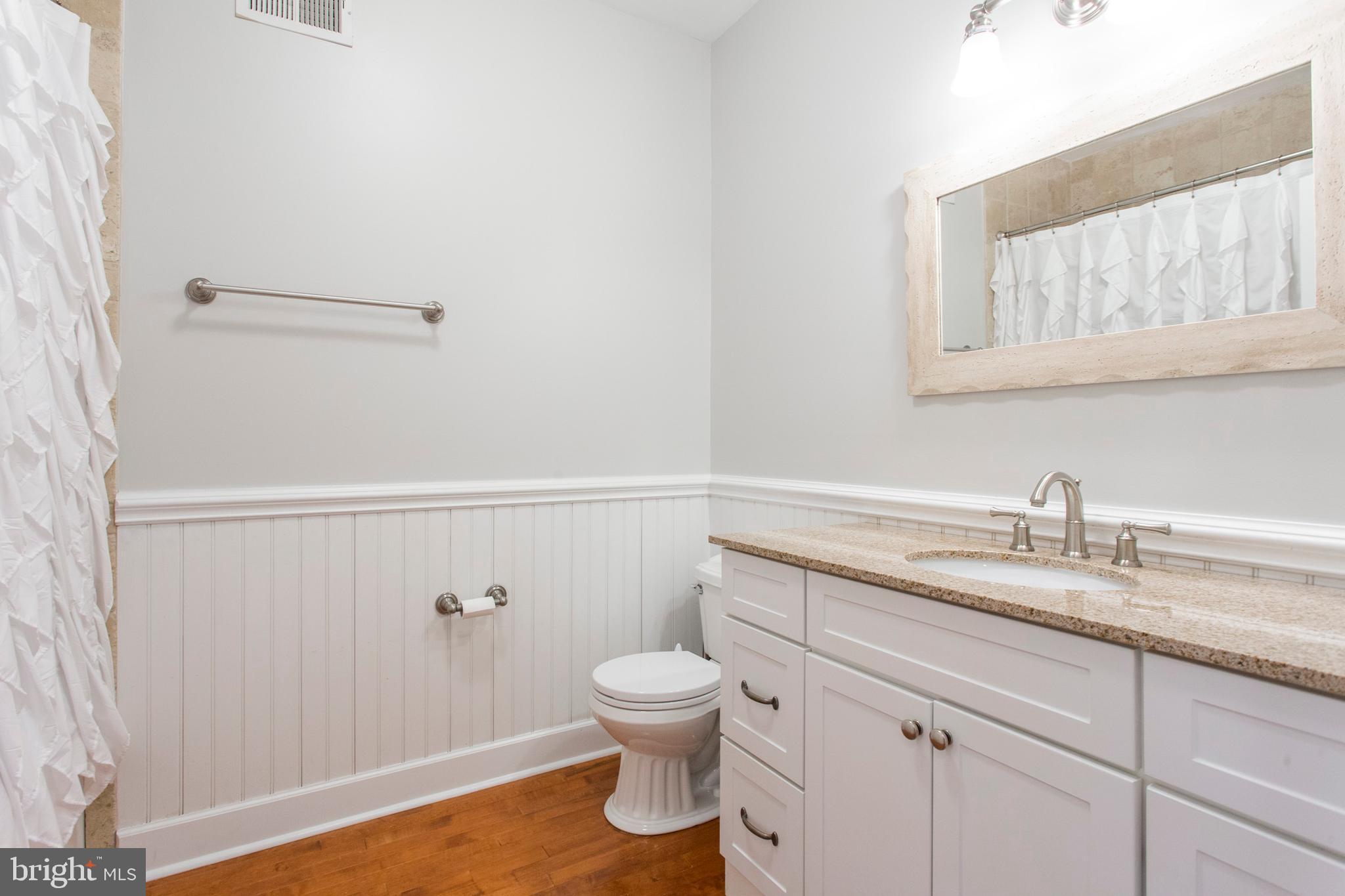 2118 Ellsworth Street Philadelphia, PA 19146 - Photo 13 of 32 a bathroom with a granite countertop sink a toilet and a mirror