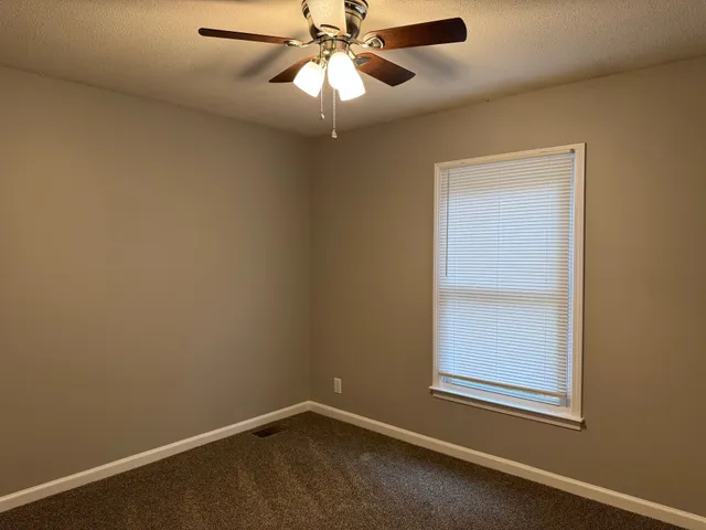 an empty room with a window and a fan