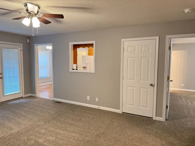 an empty room with chandelier fan and windows