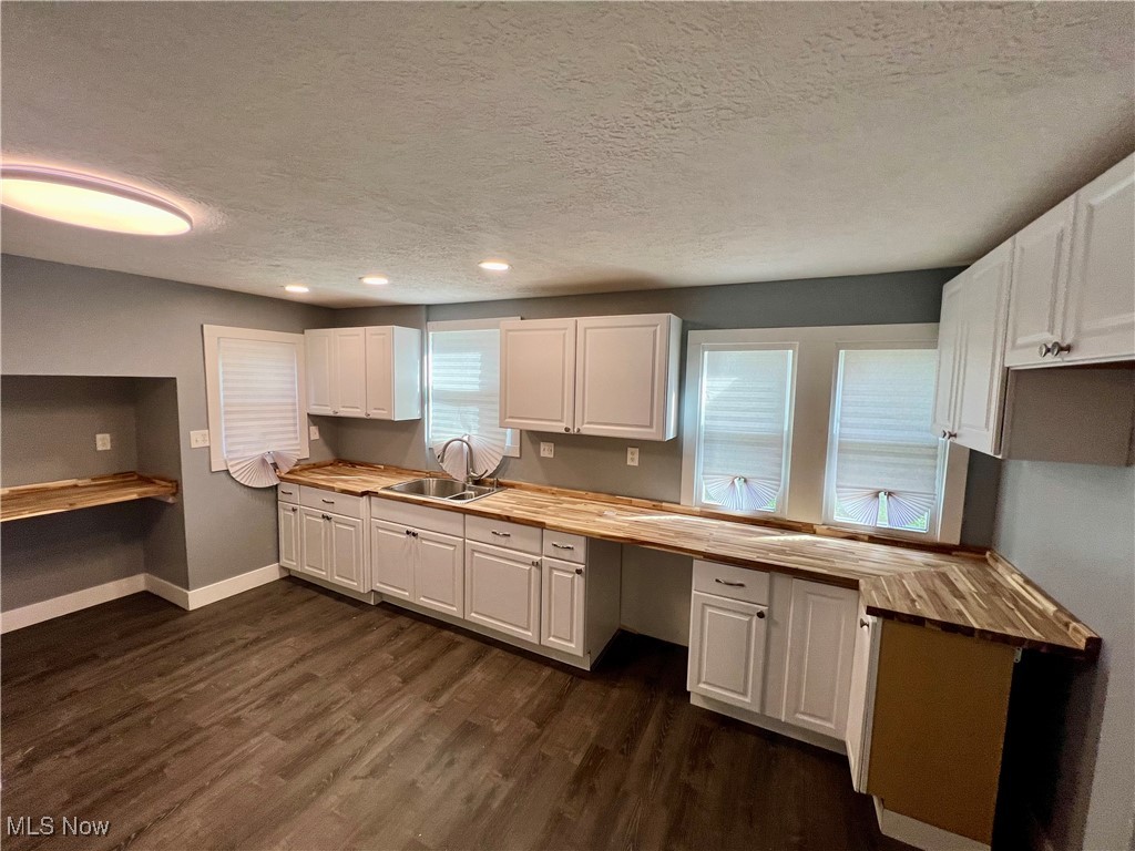 1024 Copley Road Akron, OH 44320 - Photo 8 of 31 Kitchen featuring butcher block counters, sink, white cabinets, a textured ceiling, and dark hardwood / wood-style flooring