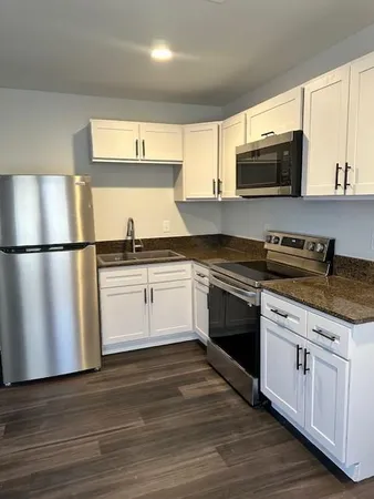 a kitchen with stainless steel appliances granite countertop a stove top oven a sink and a refrigerator