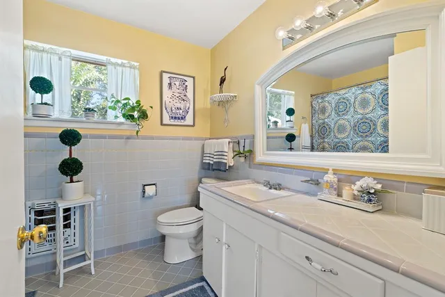 a bathroom with a granite countertop sink mirror vanity and toilet