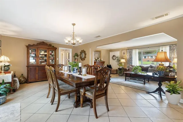 a view of a dining room and livingroom with furniture a rug a potted plant and a painting