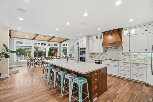 672 Perry Hollow Drive Mapleton, UT 84664 - Photo 27 of 106 Open-concept kitchen with wood-finish flooring, a substantial center island featuring a light-toned countertop, and white cabinetry