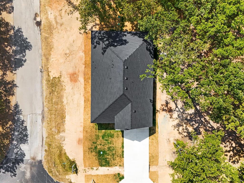4705 Point La Vista Road Malakoff, TX 75148 - Photo 35 of 40 New construction residence featuring a dark shingle roof, a white concrete driveway, and surrounding mature trees