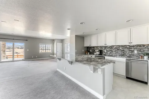a kitchen with stainless steel appliances granite countertop a stove a sink a refrigerator and white cabinets