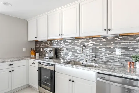 a kitchen with granite countertop white cabinets and white appliances
