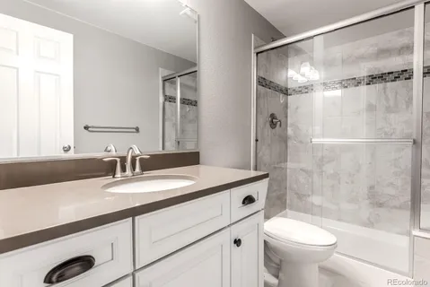 a bathroom with a granite countertop sink toilet and shower