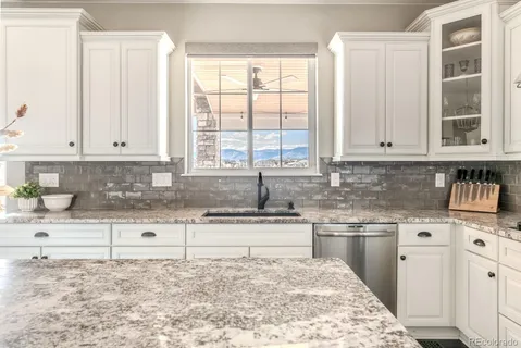 a kitchen with stainless steel appliances granite countertop a stove a sink and a white cabinets