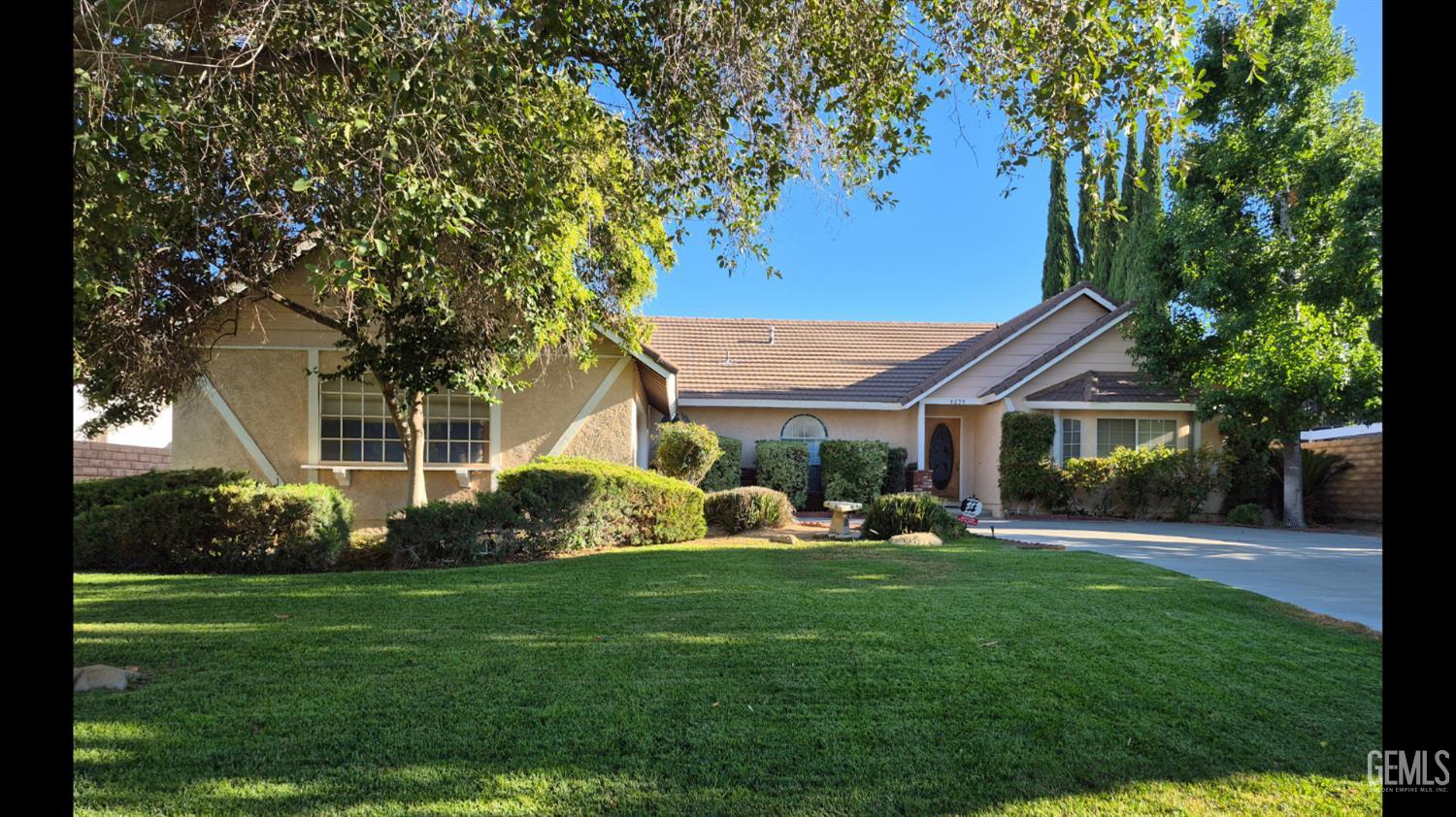 Undisclosed Address Lancaster, CA 93536 - Photo 2 of 22 a front view of a house with a garden and trees