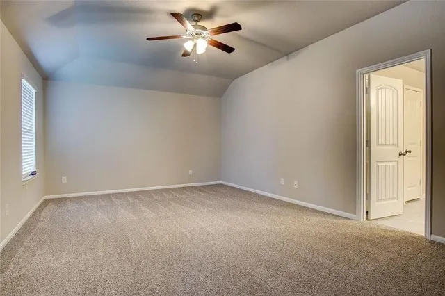 an empty room with a chandelier fan and windows