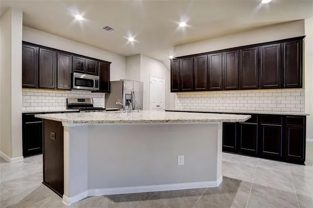 a kitchen with granite countertop wooden cabinets and stainless steel appliances