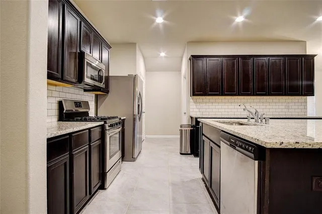 a kitchen with stainless steel appliances granite countertop a stove top oven a sink and dishwasher